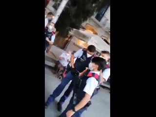 Justin hart in spain, cops try to detain a woman for not wearing her mask a dozen people throw of