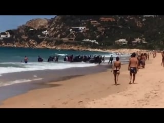 A boat full of migrants lands at a popular tourist beach in southern spain