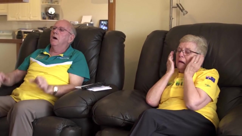 Дедушка и бабушка смотрят, как внук выигрывает золотую медаль на олимпиаде