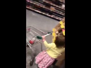 Little girl throws a bottle of wine in her toy trolley