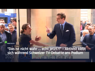 "das ist nicht wahr … echt jetzt?!" – aktivist klebt sich während schweizer tv debatte ans podium