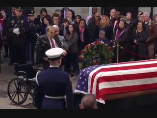 95 year old former senator bob dole helped out of wheelchair to give a final salute to fellow wwii vet george h w bush