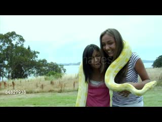 Ms, two girls holding albino snake around shoulders standing