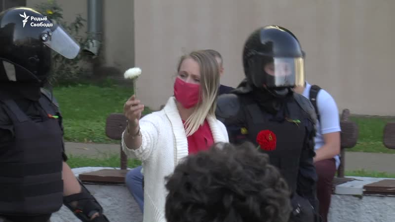 Затрыманая дзяўчына дорыць кветкі сілавікам