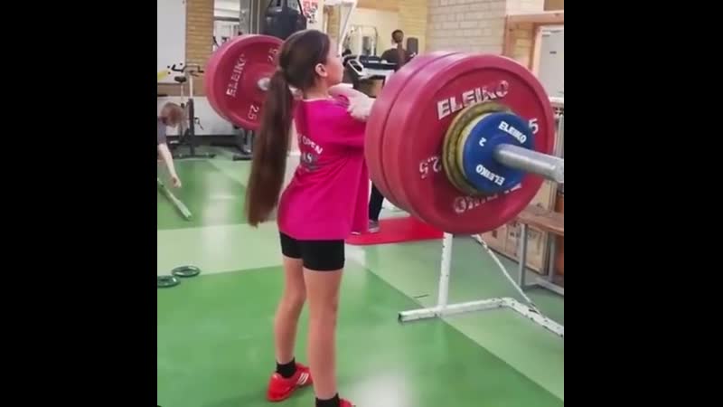 Молодая спортсменка делает толчок штанги