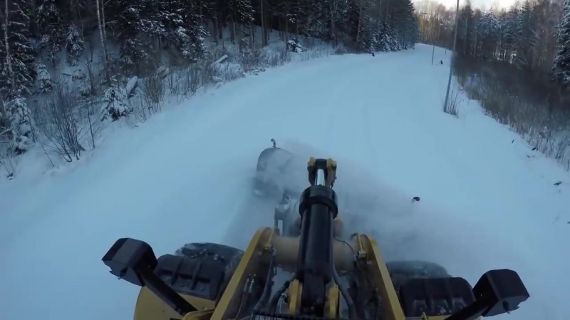 Фронтальный погрузчик с отвалом расчищает снег, вид из кабины