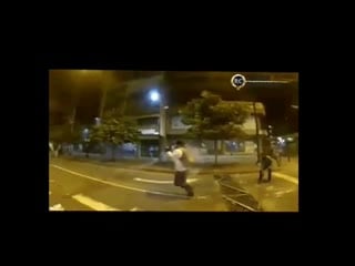 Stabilized view of a protester catching and throwing a tear gas can back towards riot police