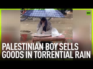 Palestinian boy sells goods in torrential rain