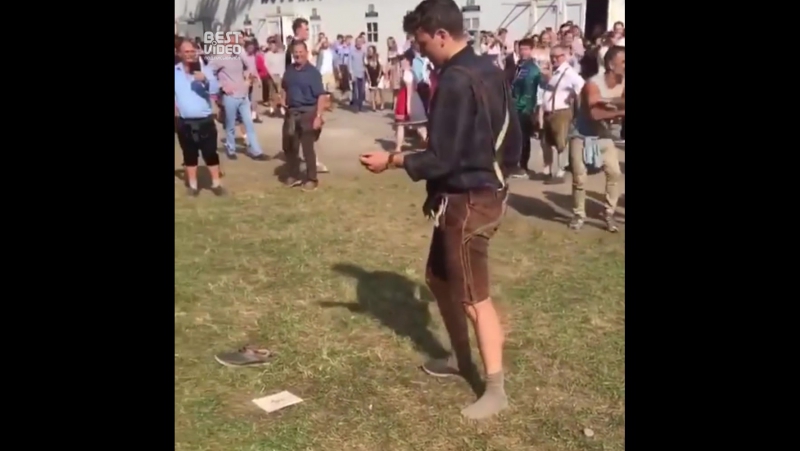 Толпа наблюдает как мужик пьяный пытается надеть кросоу и поддерживает его