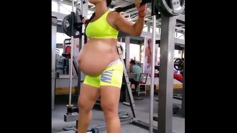 Беременная девушка приседает в тренажере смита