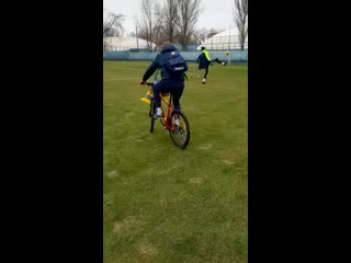 Карпин катается по полю на красном велосипеде