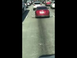 Car with protruding wire rims drives down highway 986023