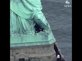 Woman who scaled base of statue of liberty detained by authorities, led back down