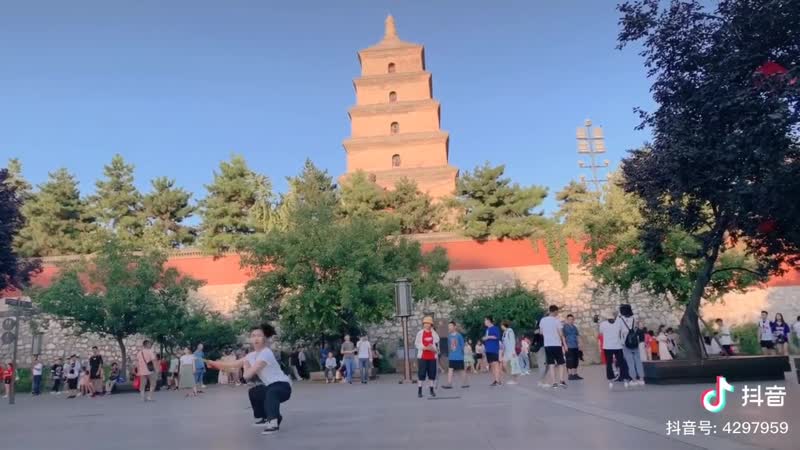 Китаянка практикует тайцзицюань с веером на фоне символа сианя большой пагоды диких гусей