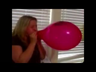 Pretty woman skillfully blows to pop a red balloon