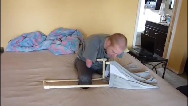 Quad amputee uses dressing assistance device (dad) to put his pants on