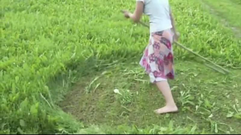 Женщина косит траву косой