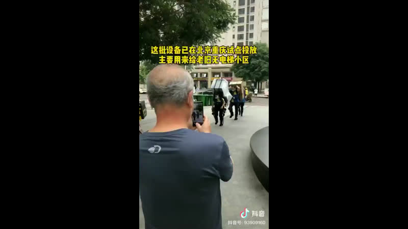 Китайский девушка курьер доставляет холодильник на пятый этаж