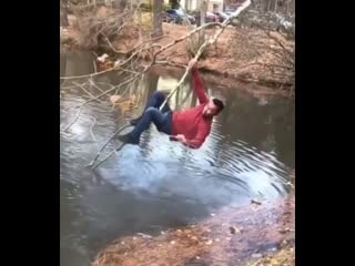 Guy climbs onto a branch out over water to get his friend’s lure unstuck