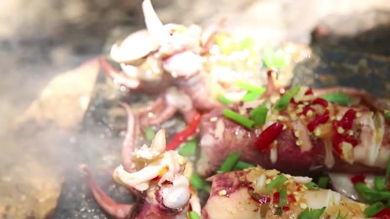 Primitive technology cooking squid on a steel for lunch in the woods wilder