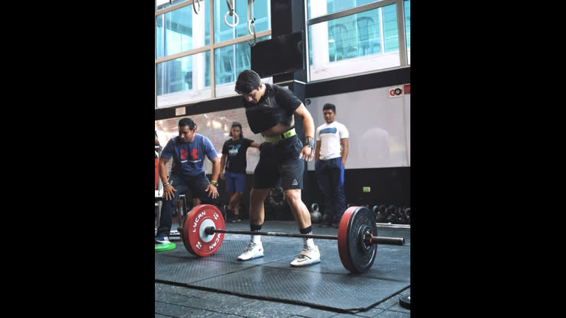 Парень делает рывок штанги одной рукой