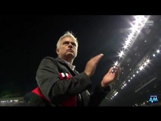 Mourinho picks up a united shirt and scarf, puts it under his arm and applauds the stretfo