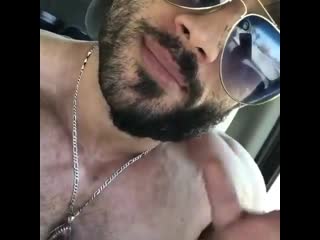 Huge hairy bodybuilder posing and flexing chest and abs in car