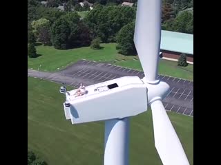 Drone captures a man sun bathing on a wind turbine with no harness on