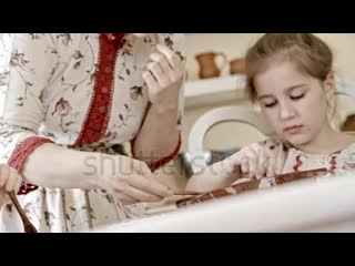 Stock footage closeup of beautiful woman in traditional russian dress pouring liquid chocolate into glass bowl whi mp4