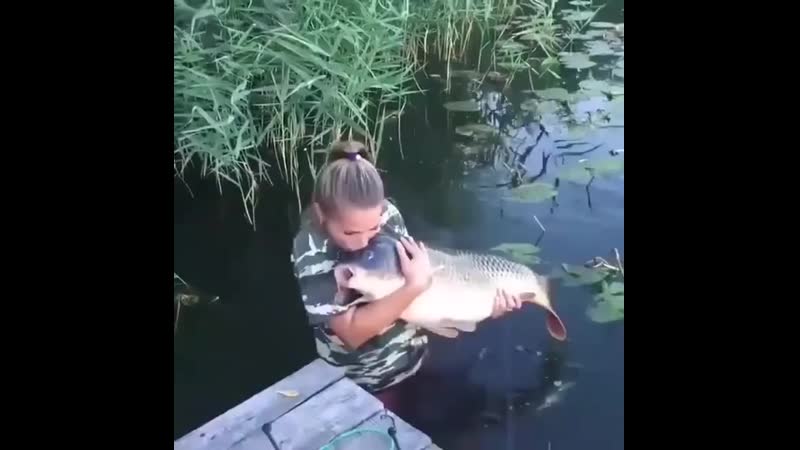 Девушка отпускает трофейного карпа в водоем