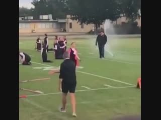 Band director protecting his band from sprinklers