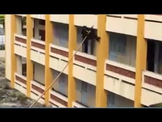 Vietnamese police officers scaling a building wall with a pole