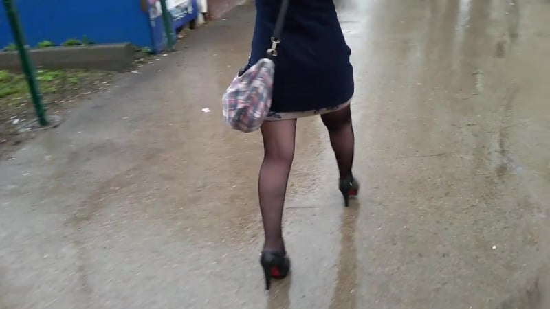 Девушка в колготках на высоких каблуках идет на останоу