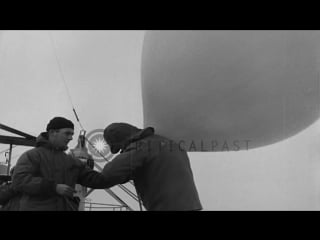 Two men hold down a helium filled balloon and ice floating in water in the ross stock footage