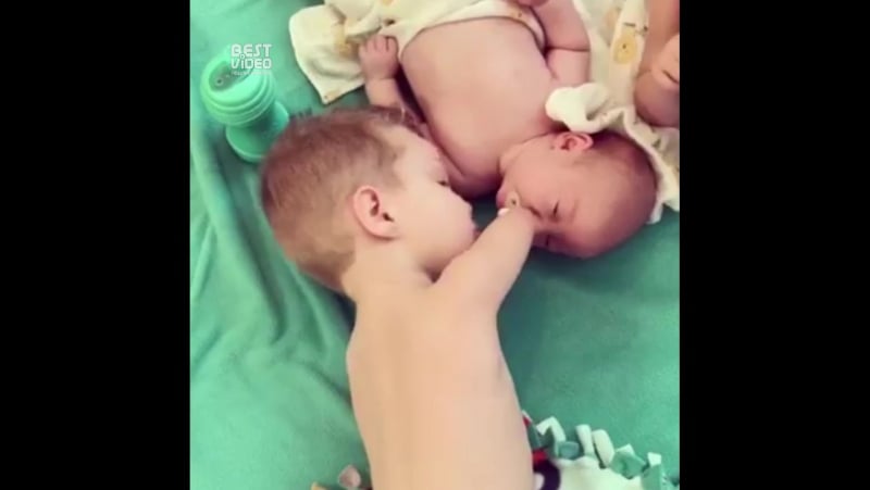 Безрукий маленький мальчик заботится о новорожденном братике