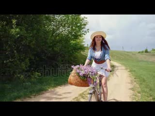 Stock footage woman in a hat travels on a bicycle with a basket full of lilac branches slow motion steadicam shot mp4