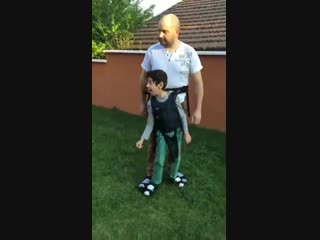 Father wears a mobility harness so his son with cerebral palsy can play too