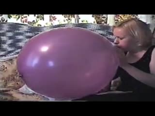 Girl blows up a purple punch balloon until it goes bang