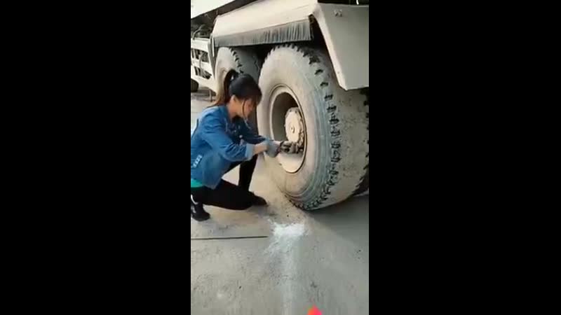 Хрупкая девушка переобувает колеса на шиномонтаже