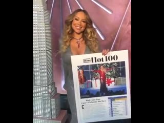 Mariah carey posing with commemorative billboard hot 100 chart after aiwfciy goes 1