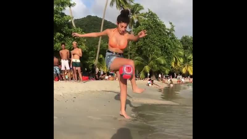 Девушка очень круто набивает мяч на берегу пляжа