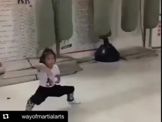 Маленькая девочка отрабатывает удары в низкой стойке