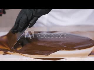 Tempering melted chocolate on natural stone woman's hands and spatula close up